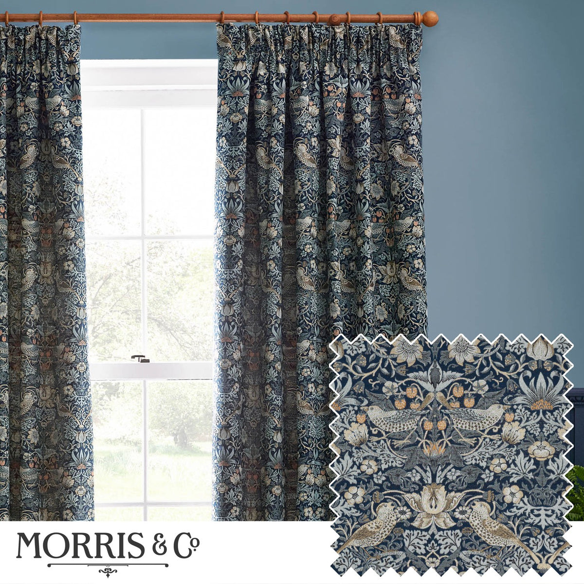 Strawberry Thief pencil pleat curtains in indigo blue, woven jacquard fabric with bird and strawberry motif, shown pleated on a wooden pole beside a window.