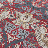 Close-up of the Strawberry Thief Jacquard Velvet Cushion in berry red, showing woven thrushes, tulips and scrolling foliage in slate blue and cream tones.