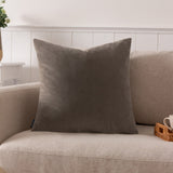 Sunningdale plain velvet cushion in mink, a warm grey-brown square 50 x 50cm design shown on a beige sofa in a living room setting.