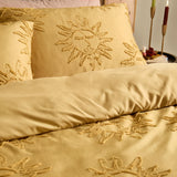 Gold polyester duvet cover set with tufted sun motifs on the duvet and pillowcases, shown on a bed in a bedroom setting.