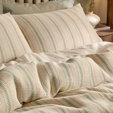 Selby Waffle Cotton Striped Duvet Cover Set in bay green and natural, shown on a bed with matching pillowcases, textured grid weave visible.