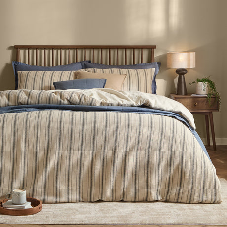 Selby waffle cotton striped duvet cover set in coal and natural on a bed with matching pillowcases, styled with blue accent bedding in a bedroom setting.