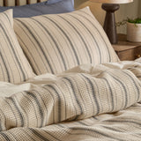 Selby waffle cotton duvet cover set with coal stripes on a natural ground, shown on a bed with matching pillowcases and a plain white sheet beneath.