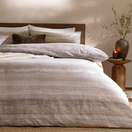 Swift Cotton Striped Duvet Cover Set in Natural, brushed cotton bedding with muted beige striped design, styled on a bed with matching pillowcases and cushions in a warm bedroom setting.