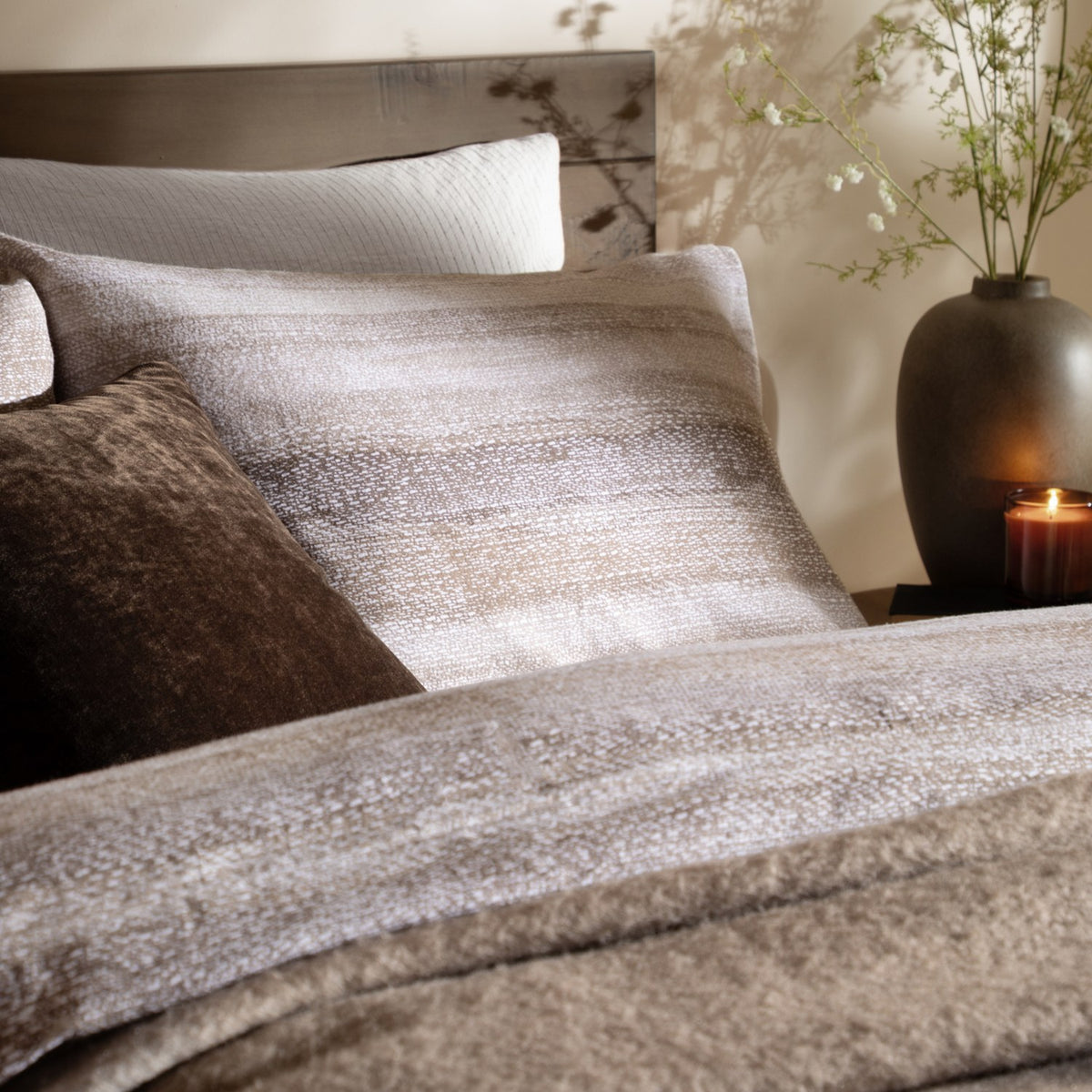 Swift Cotton Striped Duvet Cover Set in natural tones, styled on a bed with matching pillows, a brown cushion and a bedside vase with candle.