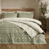 Strawberry Thief Percale Cotton Bedspread in forest green, quilted with a bird and berry pattern, shown on a bed with striped reverse folded back and matching pillow shams.