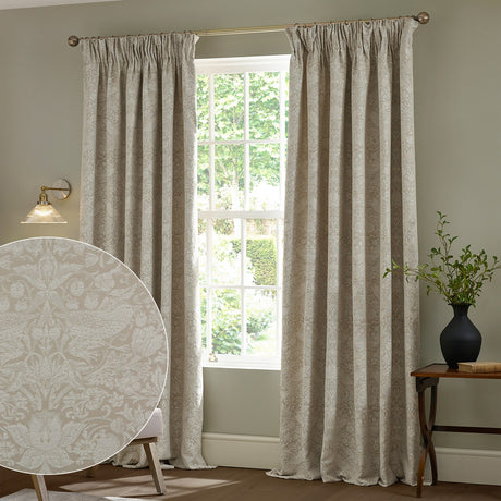Strawberry Thief Jacquard Linen Pencil Pleat Curtains in beige hung either side of a window, with a fabric swatch inset showing the woven bird and strawberry pattern.