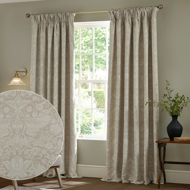 Strawberry Thief Jacquard Linen Pencil Pleat Curtains in beige hung either side of a window, with a fabric swatch inset showing the woven bird and strawberry pattern.