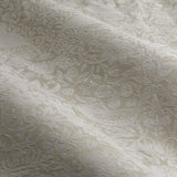 Close-up of Strawberry Thief jacquard linen pencil pleat curtain fabric in beige, showing a woven tonal pattern of strawberry plants and birds catching light across soft folds.
