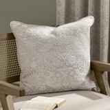Strawberry Thief Jacquard Linen Cushion in cream, woven bird and strawberry motif on a linen-toned ground with piped edge, shown on a wooden armchair.