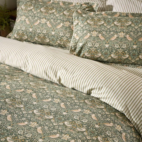 Strawberry Thief cotton duvet cover set in forest green, showing bird and floral pattern pillowcases paired with striped reverse on a made bed.