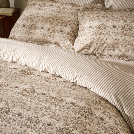 Strawberry Thief cotton duvet cover set in natural beige floral print, shown reversing to a fine striped percale on pillowcases and bed.