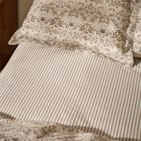 Strawberry Thief Percale Cotton Fitted Sheet in Natural, showing a narrow brown and cream stripe design paired with the coordinating floral pillowcases on a bed.