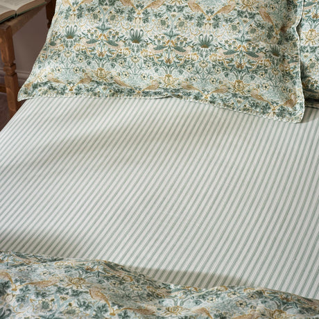 Strawberry Thief Percale Cotton Fitted Sheet in sage green, fine narrow stripe pattern, shown on a bed with matching floral pillowcases and duvet cover.