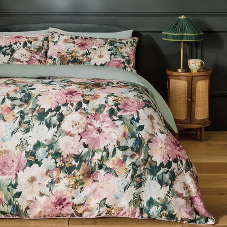 Tahiti Cotton Floral Duvet Cover Set in Spring, shown on a bed with matching pillowcases featuring pink and cream blooms on green foliage, paired with sage green sheets in a bedroom setting.