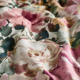 Tahiti Cotton Floral Duvet Cover Set in Spring, close-up of cotton sateen fabric with watercolour blooms in dusky pink, cream and amber against deep green foliage.