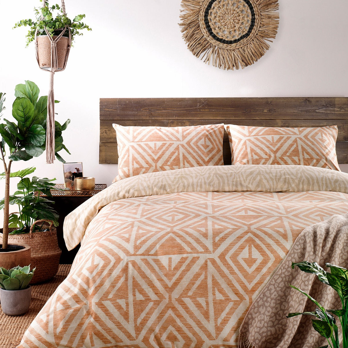 Tanza Geometric Animal Duvet Cover Set in terracotta and cream, styled on a bed with matching pillowcases in a rustic bedroom with wooden headboard.