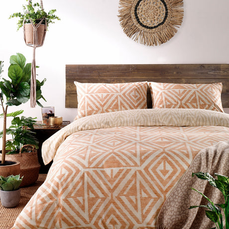 Tanza Geometric Animal Duvet Cover Set in terracotta and cream, styled on a bed with matching pillowcases in a rustic bedroom with wooden headboard.