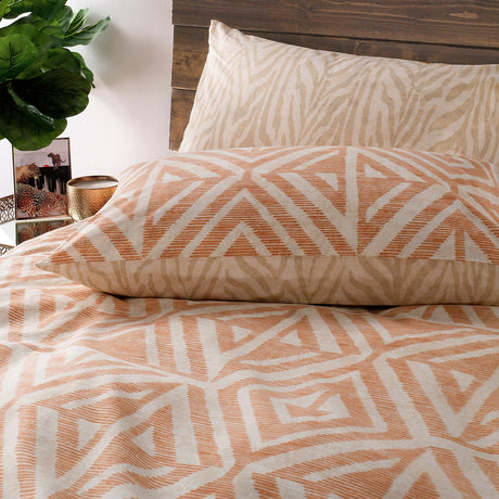 Tanza Geometric Animal Duvet Cover Set in Terracotta, showing the terracotta and cream geometric diamond print alongside a reverse sandy animal stripe pattern on a bedroom pillow and duvet.