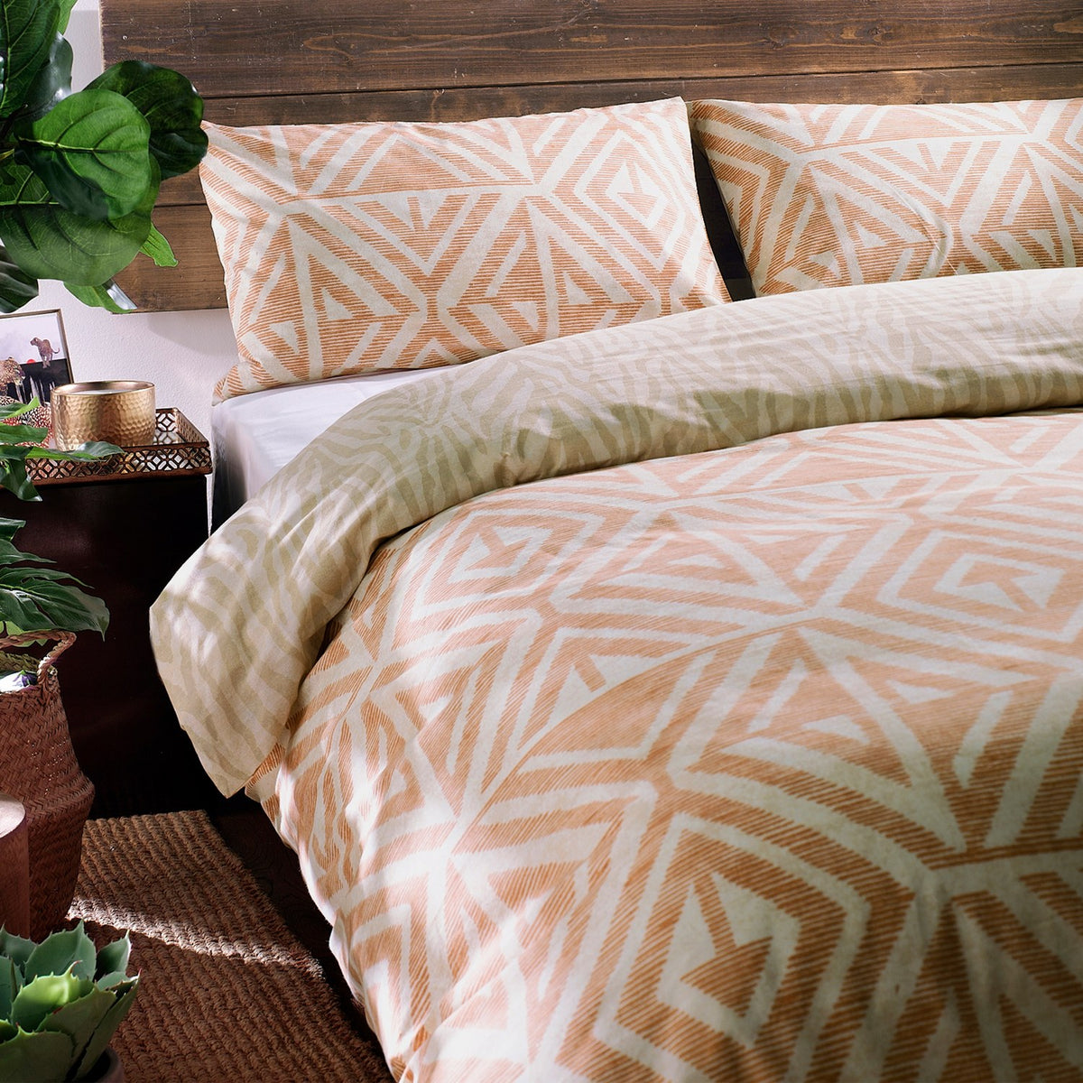 Tanza Geometric Animal Duvet Cover Set in terracotta and cream, styled on a bed with matching pillowcases in a rustic bedroom setting.