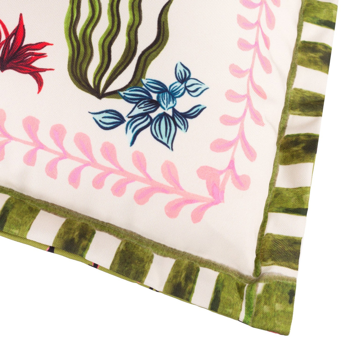 Corner detail of the Tiger Dream reversible polyester cushion, showing the calmer reverse side with blue and red foliage, pink fern trim, and a green and cream striped border.