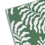 Close-up corner view of the Tocorico Jacquard Jungle Rug in green, showing a bold leaf pattern in green and white woven polypropylene with a finished edge, on a plain white background.