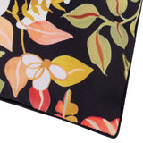 Close-up of the Tropical Bloom Lost reversible polyester cushion corner in black, showing coral, pink, olive and mustard leaf and floral print with piped edge finish.