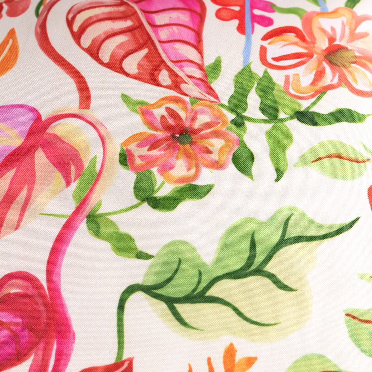 Close-up of the Tropical Bloom Reversible Polyester Cushion, showing a hand-illustrated tropical leaf and flower print in pink, coral, orange and green on a natural cream ground.