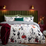 Trick or Treat reversible duvet cover set on a bed with Halloween-print witches, skeletons and pumpkins, paired with black and white striped pillowcases in a dark red bedroom.