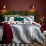 Trick or Treat reversible duvet cover set on a bed, monochrome striped side shown with a Halloween-print edge peeking out, styled with a green headboard and burgundy throw.