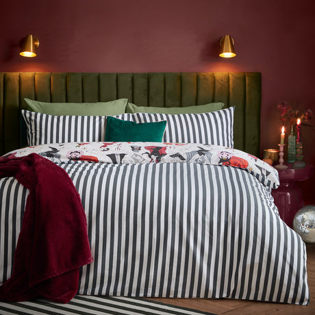 Trick or Treat reversible duvet cover set on a bed, monochrome striped side shown with a Halloween-print edge peeking out, styled with a green headboard and burgundy throw.