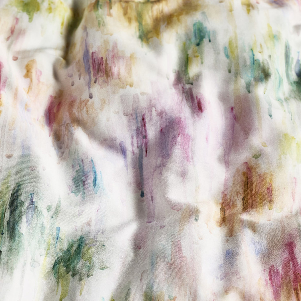 Trueno cotton duvet cover close-up showing an abstract watercolour print of vertical brushstrokes in pink, purple, green, gold and teal on a cream ground.