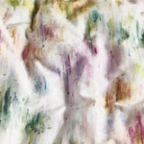 Trueno cotton duvet cover close-up showing an abstract watercolour print of vertical brushstrokes in pink, purple, green, gold and teal on a cream ground.