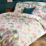 Trueno Cotton Abstract Duvet Cover Set in multicolour, styled on a bed with a teal cushion and matching pillowcases against a dark teal bedroom wall.