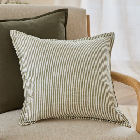 Truro Striped Cotton Cushion in moss green, showing a slub-textured cotton cover with narrow woven stripes and a flanged edge, styled on a beige armchair with an olive cushion behind.