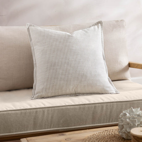 Truro Stripe Reversible Cotton Cushion in natural beige on a linen sofa, square shape with narrow yarn-dyed stripes and piped edge trim.