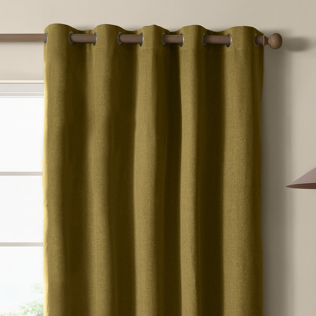 Olive green blackout eyelet curtain in plain woven polyester, shown hanging on a wooden pole with metal grommets beside a window.