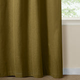 Forest green eyelet curtain in plain woven blackout fabric, shown hanging beside a window with a cream wall and skirting board.
