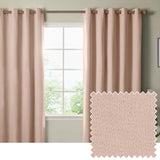 Blush pink eyelet blackout curtains with woven texture hang from a bar either side of a window in a bedroom, shown with a matching fabric swatch.