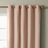 Blush pink eyelet curtain panel with woven texture and metal grommets on a wooden rod, hung against a sage green wall beside a window.