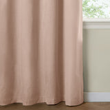 Blush pink blackout eyelet curtain in a woven polyester fabric, shown falling in soft folds beside a window with a cream wall and skirting board.