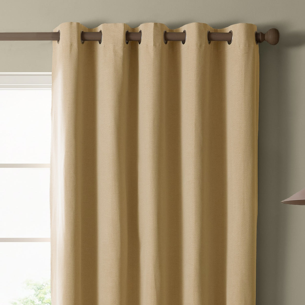 Yellow blackout eyelet curtain in plain woven polyester fabric, shown hung on a wooden pole with metal grommets beside a window in a living room setting.