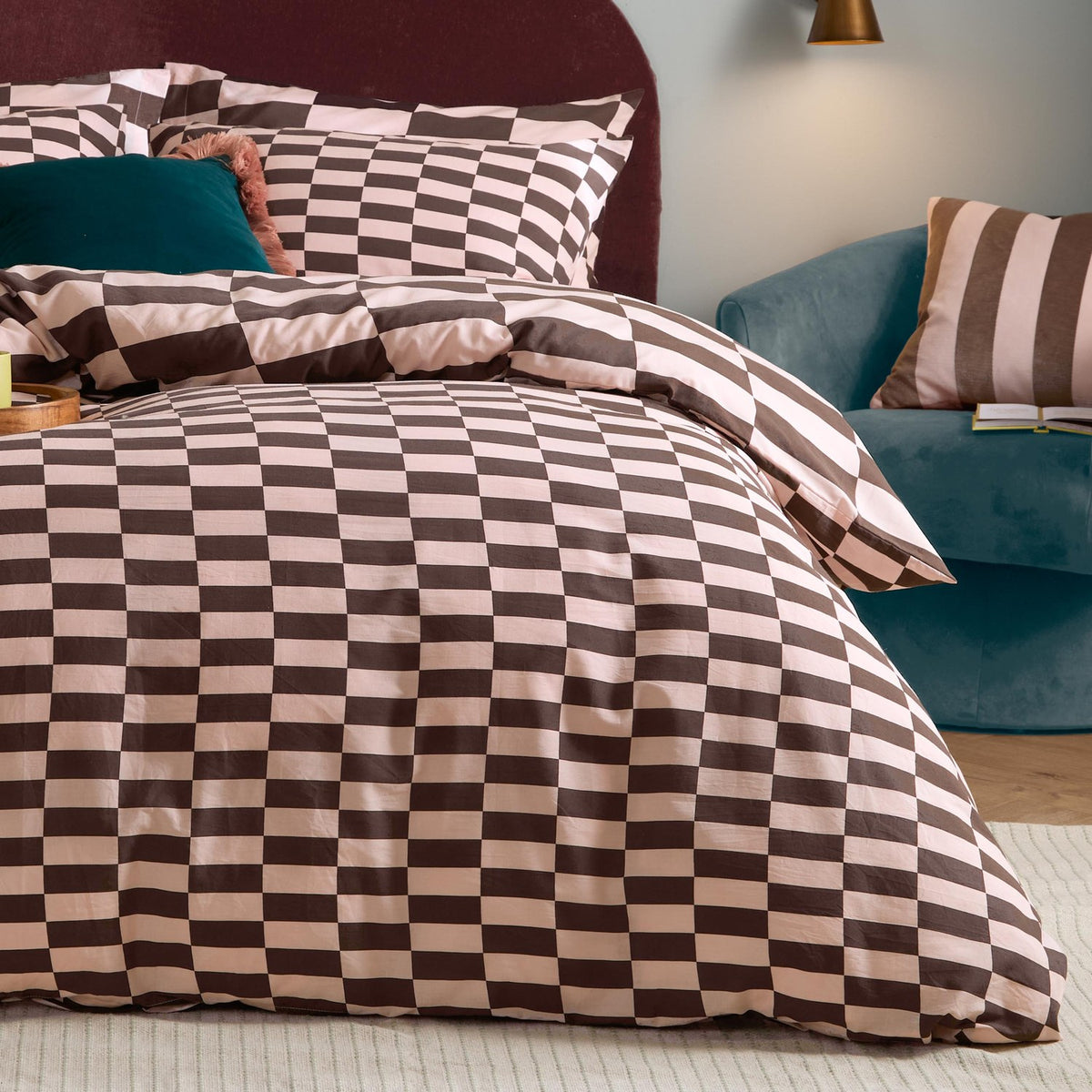 The Ultimate Checkerboard Duvet Cover Set in Berry Brownie shown styled on a bed with matching pillowcases in a pink and chocolate brown checkerboard print, in a bedroom setting.