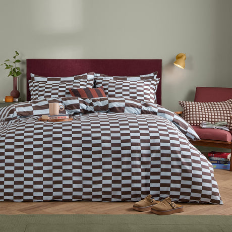 The Ultimate Checkerboard Check Duvet Cover Set in Blueberry Muffin, shown on a bed with a burgundy headboard, featuring a reversible blue and brown checkerboard print with matching pillowcases.