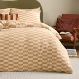 Caramel latte checkerboard duvet cover set on a bed with matching pillowcases and a striped accent cushion, styled in a bedroom beside a rust-toned chair.