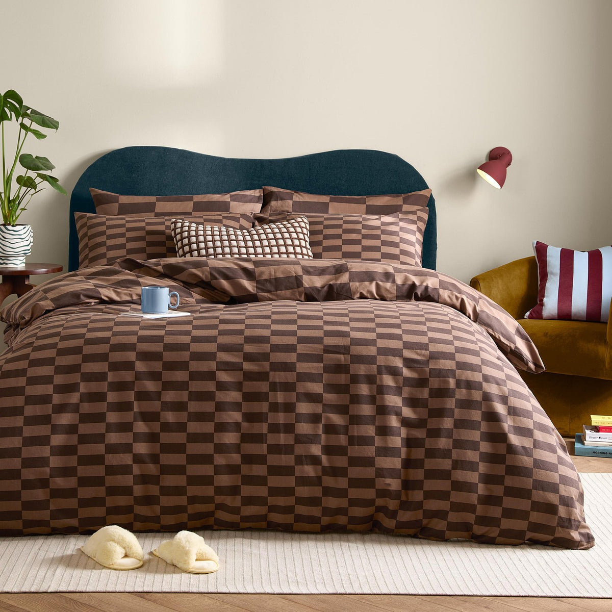 The Ultimate Checkerboard Check Duvet Cover Set in Chocolate Truffle brown on a bed with matching pillowcases and cushions, styled in a bedroom with a teal headboard.