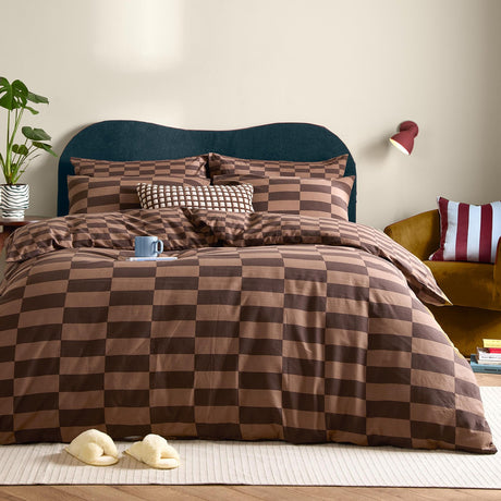 The Ultimate Checkerboard Check Duvet Cover Set in Chocolate Truffle brown dresses a bed with matching pillowcases and a textured cushion in a modern bedroom setting.