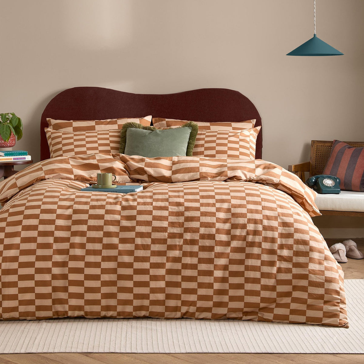The Ultimate Checkerboard Check Duvet Cover Set in Pumpkin Spice, shown on a bedroom bed with matching pillowcases in an orange and sand check pattern, styled with a green accent cushion.