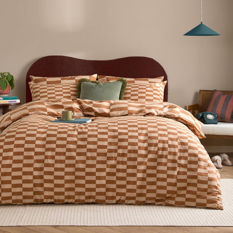 The Ultimate Checkerboard Check Duvet Cover Set in Pumpkin Spice, shown on a bedroom bed with matching pillowcases in an orange and sand check pattern, styled with a green accent cushion.