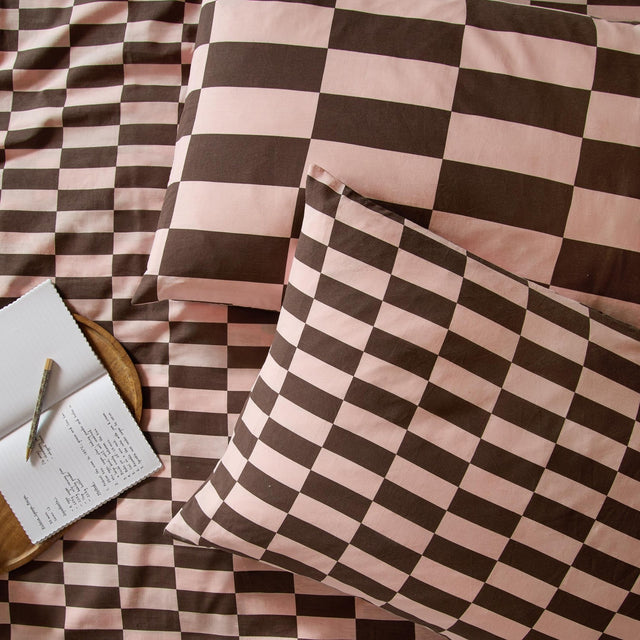 Checkerboard cotton blend pillowcase pair in Berry Brownie, shown on bedding with pink and brown block check pattern in matching large and mini scales.